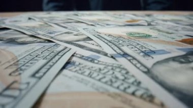 100 dolarlık banknotlar yığının üzerine düşüyor. Kağıt, Amerikan para biriminin masaya saçıldığını gösteriyor. Yüzeyde Benjamin Franklin 'in portresi olan 100' lük yığın. Para nakit geçmişi.