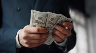 Businessman hands counting pack of american dollars close up. Unknown owner in luxury suit calculating paper bills indoors. Closeup man fingers holding lot of hundred banknotes. Business concept.