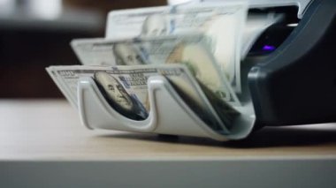Modern automatic machine counting american dollar bills denomination of hundred close up. Electronic equipment for paper money calculation. Device for bank cash currency operations. Finance concept