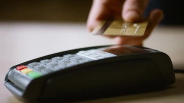 Banka terminalinde bağlantısız kredi kartı ödemesi. NFC teknolojisiyle satın almak için el ile ödeme yapan adam okuyucuya dokunuyor. Bilinmeyen müşteri kablosuz para transferini kullanıyor. Nakitsiz işlem.