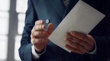 Unknown businessman taking euro bills from envelope indoors close up. Hands rich man in elegant suit holding pack banknotes of european currency denomination fifty. Manager received monetary bribe.