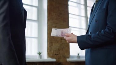 Patron ofis toplantısındaki başarılı çalışanlara prim veriyor. Yakın plan. Bilinmeyen yönetici profesyonel işçiyi ödüllendiriyor. Ödeme sonrası nakit olarak el sıkışan işadamları.
