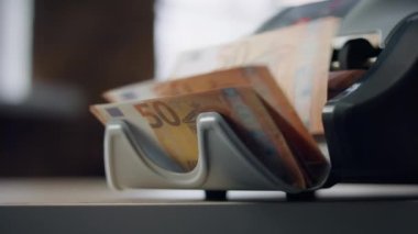 Modern electronic counter calculating euro bills denomination of fifty close up. Automatic calculation machine counting european currency banknotes indoors. Bank equipment for money cash operations.