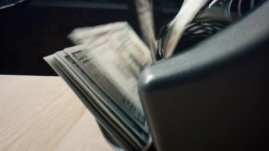 Masada kağıt dolar sayma makinesi var. Otomatik ekipmanla hesaplanan Amerikan para birimi banknotlarının makro görüntüsü. Para hesaplaması için elektronik banka sayacı. Muhasebe kavramı.