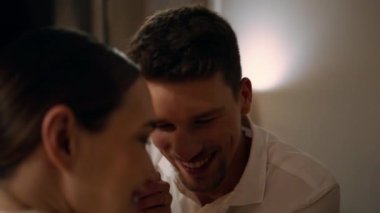 Loving couple touching foreheads at evening room closeup. Happy man cheerful woman holding hands at night place. Young newlyweds romantic date. Positive lovers sitting together at restaurant interior