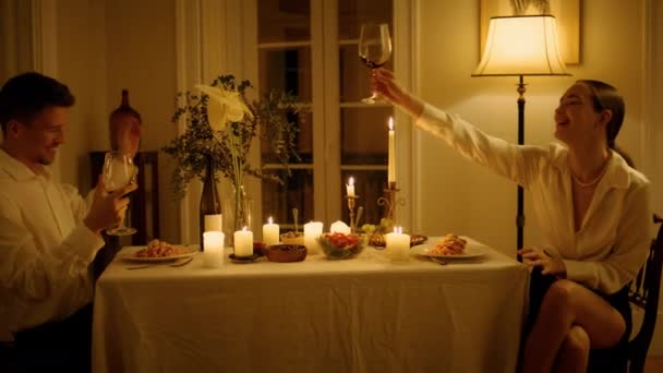 Χαμογελαστό Ζευγάρι Που Κλίνει Ποτήρια Κρασιού Στο Κοντινό Τραπέζι Κεριά — Αρχείο Βίντεο