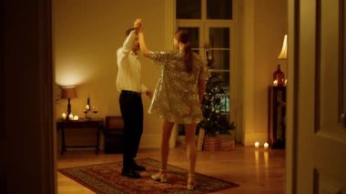 Sensual couple dancing Christmas eve room. Tender lovers moving together in party illumination light. Charming man woman celebrating New Year at decorated apartment. Pair bonding at xmas tree place 