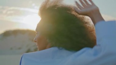 Yaz akşamları çölde dans eden çekici bir kız. Beyaz elbiseli, duygusal olarak dokunan Afro-Amerikan kadın. Odaklanmış esmer dansçı yüzü yakından..