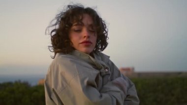 Girl resting evening seaside closeup. Thinking casual woman posing admiring dawn landscape on cold windy shore. Beautiful dreamy millennial contemplate life enjoy solitude at night. Serene quiet place