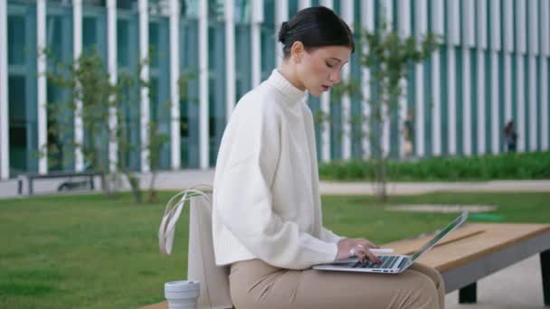 Focused Young Woman Typing Laptop Sitting Bench Modern Office Building — Stock video
