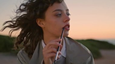 Creative girl holding paintbrush at sunset sky closeup. Focused artist composing looking idea inspiration on windy evening. Beautiful talented woman enjoying hobby drawing outdoors. Art people concept