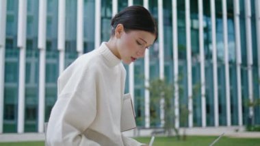 Worried woman freelancer working laptop sitting on bench city square close up. Attractive anxious businesswoman typing on notebook keyboard. Serious lady solving business problems remotely outdoors.