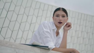 Successful young business girl posing outdoors alone close up. Attractive stylish woman standing in front modern office building leaning on fence. Confident professional manager enjoy work break.