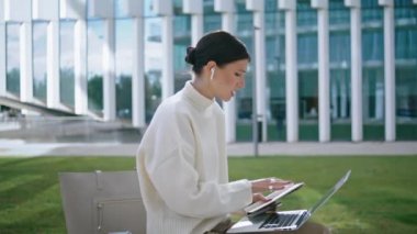 Confident girl talking video conference sitting bench near modern office close up. Young stylish business woman discussing work issues in online chat remotely. Lady coach speaking on webinar outdoors.