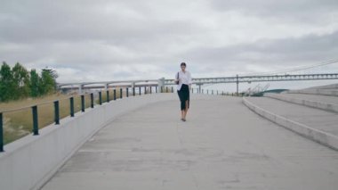 Elegant model walking empty road in front cloudy gray sky. Stylish confident business woman hurrying work wearing white shirt. Attractive young lady going on city street alone. Girl enjoy work break.