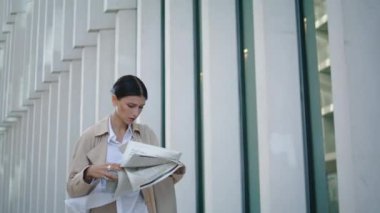 Ciddi ciddi sabah gazetesi okuyan ofis işleriyle meşgul bir kadın. Çekici genç bir iş kadını elinde mali basınla modern şehir binasının yakınında yürüyor. Akıllı kadın makaleye odaklanmış..