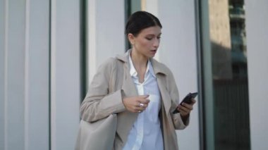 Busy elegant girl received phone message going on work near modern building closeup. Attractive young business woman walking street looking telephone screen. Confident lady hurrying office with mobile