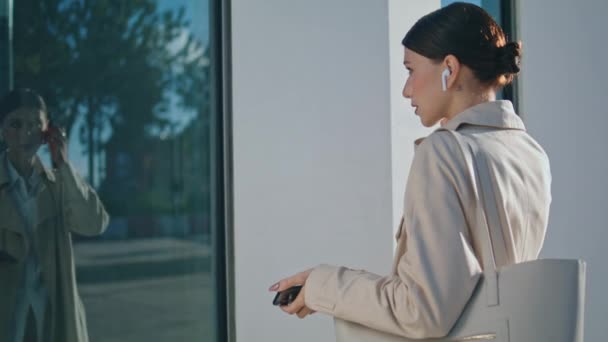 Ung Affärskvinna Som Tar Trådlösa Hörlurar Och Tittar Fönsterreflektion Utomhus — Stockvideo