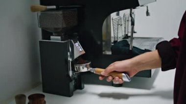 Unknown barista pouring ground coffee in coffeemaker portafilter close up. Man hand holding filter filling aromatic grinding powder. Professional electric grinder preparing ingredients caffeine drink.