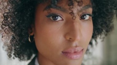 Closeup attractive woman face with beautiful exotic dark eyes. Portrait of gorgeous african american girl looking camera. Curly natural brunette model posing confidently. Beauty fashion concept.