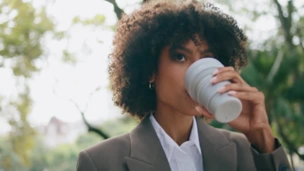 漂亮的豪华女商人在纸杯中喝咖啡时走得很近 典型的成功的忙碌的非洲裔美国女士喜欢匆忙的热饮工作 曲线迷人的女孩去城市公园 — 图库视频影像