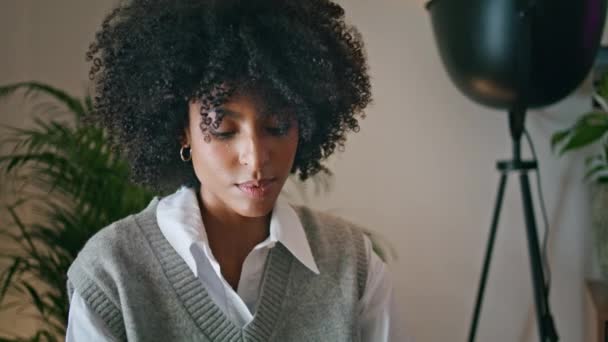 美丽而悠闲的非洲裔美国黑发人的画像 坐在舒适的室内 一个迷人的女人 面带微笑地凝视着相机 在现代咖啡馆里装扮得很迷人的卷曲女郎 — 图库视频影像