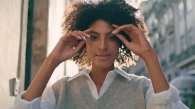 Güneşli şehir caddesinde yürüyen çekici kahverengi tenli kadın. Yaklaş. Çekici Afro-Amerikan modeli şehir gezintisinde şık kıyafetler giyerek poz veriyor. Rahatlamış kaygısız kız gülümseyen kamera.