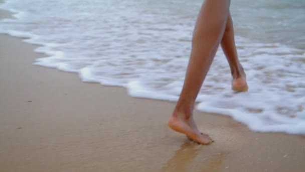在海浪中行走的女人的脚特写 不认识的爱玩的女孩一个人在海滩度假 身份不明的非洲裔美国游客赤脚玩水 浪漫的节日气氛概念 — 图库视频影像