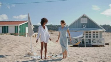 Deniz kenarındaki evlerde dans eden gülümseyen kızlar. Igbt çifti kumsalda hafta sonunu birlikte geçiriyorlar. Çok ırklı iki çekici turist okyanus pikniğinde eğleniyor..