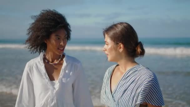 在夏日阳光的特写下 时髦的女孩在海滩聊天 在海浪中分享秘密的情侣们笑得很开心 美丽的多文化女性在岸上度过周末 结合友谊的概念 — 图库视频影像