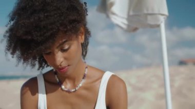 Kapalı plaj üzgün kız deniz kıyısında yalnız dinleniyor. Stresli, güzel bir kadın kayıp aşkı düşünüp endişeleniyor. Rüzgarlı bir günde çekici, şık, Afro-Amerikan dinlenme sahili. Okyanusta dalgın bir kadın.