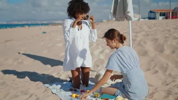 快乐的朋友在沙滩上拍照 两个女朋友在海滨共度周末 快乐的非洲裔美国人有乐趣拍照的爱情伴侣 妇女友谊概念 — 图库视频影像
