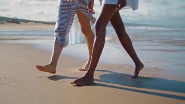 情侣腿走在海滩特写 在夏日的早晨阳光下 苗条身材的姑娘们尽情享受着海滨之旅 未被承认的多文化伴侣一起在海滨休息 平静的假期气氛 — 图库视频影像