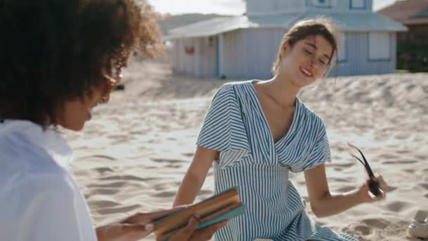 Przyjaciele Spędzający Czas Plaży Rozmawiający Książce Zbliżenie Uśmiechnięta Atrakcyjna Dziewczyna — Wideo stockowe