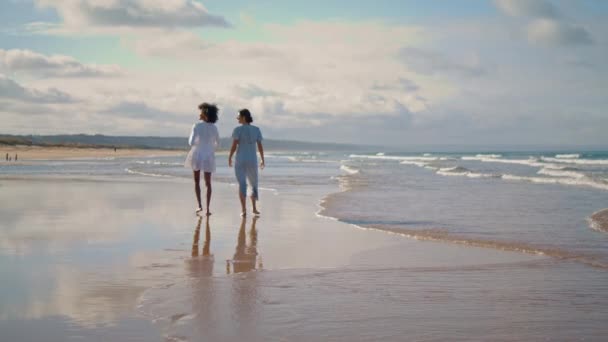在夏日阳光下 一对女同性恋夫妇在海滩散步 两个最好的朋友在海滨休息 环顾四周 放宽了多民族妇女在海滨度假的限制 旅游胜地概念 — 图库视频影像