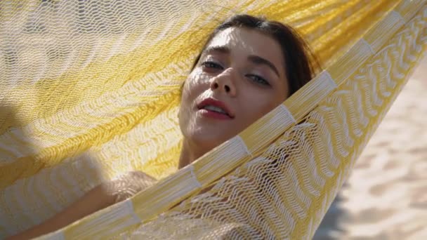 漂亮的女孩穿着比基尼特写的吊床休息 无忧无虑的女人躺在海滩休息室里看着相机 吸引和平的游客 在海滨享受暑假 宜人的阳光灿烂的周末 — 图库视频影像