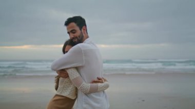 Carefree newlyweds cuddling on evening beach closeup. Smiling man kissing positive woman tenderly on beautiful marine summer nature. Affectionate couple enjoying moment together on sunset seacoast