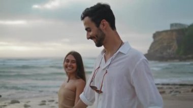 Carefree lovers walking on sandy beach closeup. Smiling girl relaxing with positive guy on beautiful summer nature. Affectionate couple looking each other enjoying tender moment together on seacoast