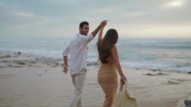 Love couple running ocean beach together closeup. Two people walking water shore outside. Ethnic spouses laughing on romantic date outdoors. Smiling adults going out sea coast. Nature leisure concept 