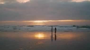 Sweethearts silhouettes walking sunbeams sea landscapes. Affectionate people enjoying romantic date evening nature. Loving tourists relaxing on honeymoon vacation. Spouses celebrating on ocean coast