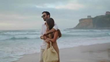 Affectionate sweethearts embracing sea landscapes closeup. Two people enjoying romantic nature date. Walking tourists talking on honeymoon vacation. Spouses hugging on ocean coast. Relax concept 