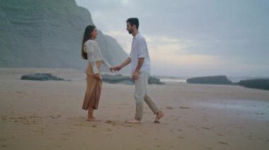 Romantic man proposing marriage to woman at evening beach. Young lovers enjoying time together. Enamoured guy kneeling down with wedding ring at seashore. Emotional couple celebrating engagement