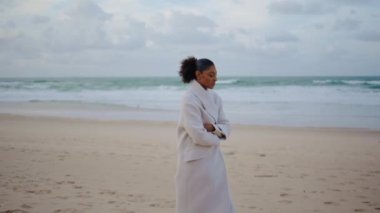 African american woman strolling ocean shore. Thoughtful traveler watching waves relaxing on cold autumn trip. Black hair lonely girl going contemplating breakup divorce. Solitude sorrow concept.