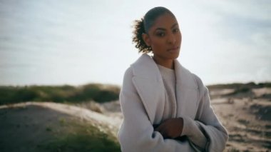 Unhappy african american thinking life problems. Serious curly model look camera resting ocean beach in sunlight alone. Worried beautiful woman taking break considering career divorce on weekend.