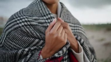 Closeup woman chest walking windy beach. African american hands adjusting scarf getting warm on cold weather. Calm beautiful woman strolling relaxing alone. Peaceful tourist feeling comfy on trip