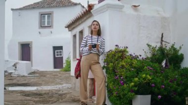 Tatilde şehir mimarisine hayran olan bir turist. Güzel kız yaz aylarında beyaz evlere yaslanarak dar sokaklara poz veriyor. Güzel rüya gören kadın, eski kasabada dinlenen analog kamerayı tutuyor. Hobi seyahat konsepti