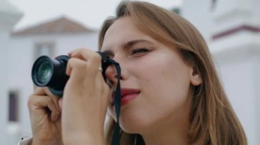Kapanış turisti eski moda kamerayla fotoğraf çekiyor. Sarışın kız çekimlerden sonra resimlere bakıyor. Şehri keşfeden çekici şehir gezgini. Güzel kadın fotoğrafçı tatilin tadını çıkarıyor