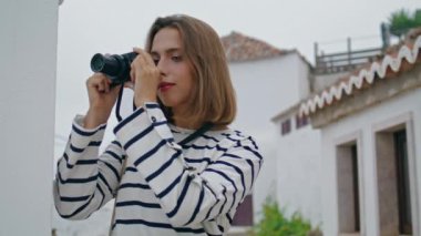 Beyazlatılmış evlerde fotoğraf çeken bir kız. Akdeniz sokaklarında gezen güzel turistler tatil anılarını resmediyor. Güzel sarışın çekimleri kontrol ediyor. Hobi ilham konsepti.