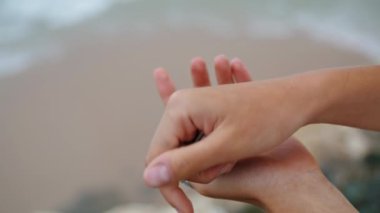 Okyanus kıyısında deniz kabuğunu tutan eller. Tatil hatıraları. Tanınmayan oyuncu kız tropikal sahilde midye saklıyor. Turistler hafta sonları dinlenmenin keyfini çıkarırlar..