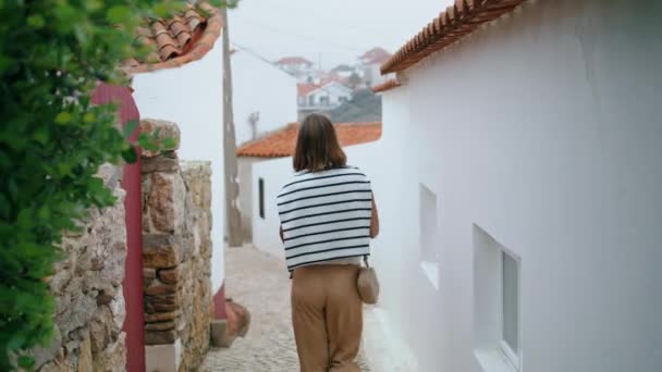 一个浪漫的女孩走在一条狭窄的老街后视镜上 暑假时 无忧无虑的游客探索欧洲城市的白色洗浴建筑 未被认可的年轻女子周末游览乡村 — 图库视频影像